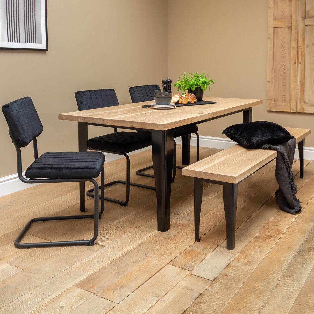 A solid oak dining table on a black metal base.
